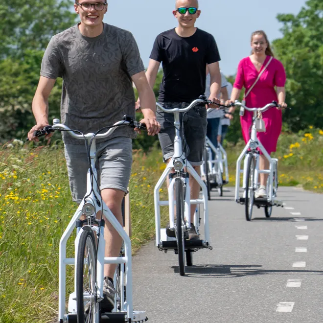 A group of friends riding walking bikes in a line along a cycle path