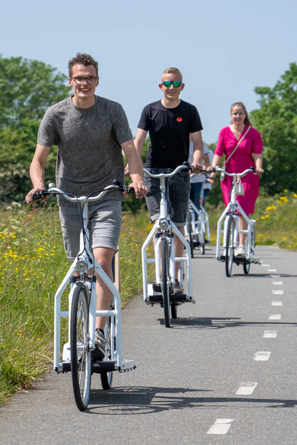 A group of friends riding walking bikes in a line along a cycle path