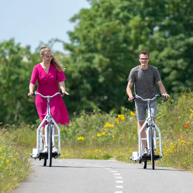 Zwei Personen mit dem Laufrad auf einem Radweg im Grünen